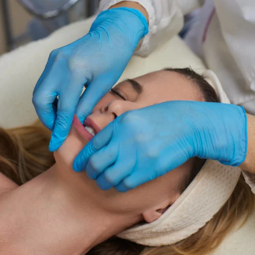 Fotografía de una mujer a la que un sanitario le sujeta la boca con unos guantes