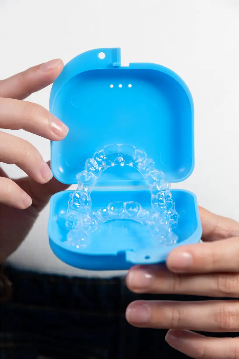 Fotografía de unas manos sujetando una caja azul con unos alineadores invisalign