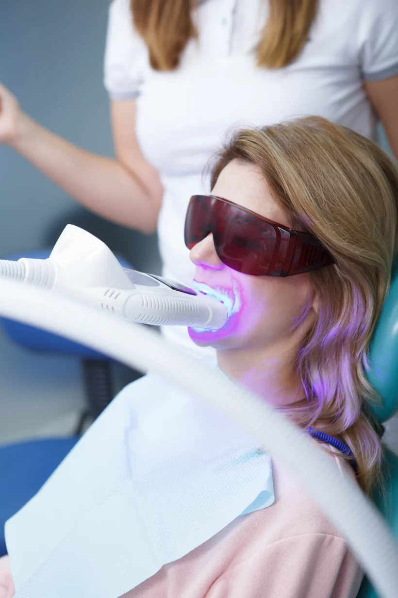 Fotografía de una mujer recibiendo tratamiento de blanqueamiento dental con láser